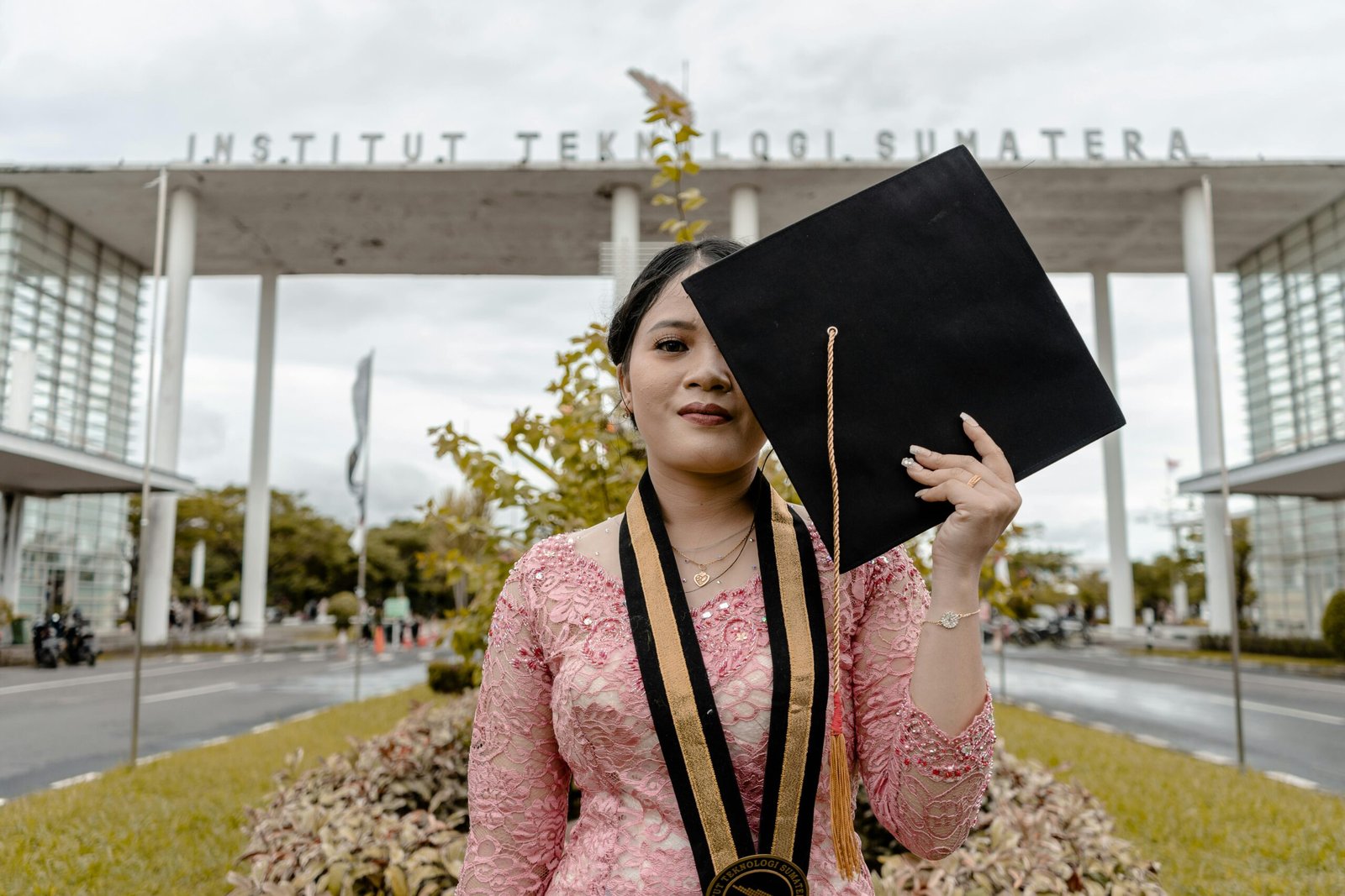 Asian female graduate posing with cap at Institut Teknologi Sumatera.